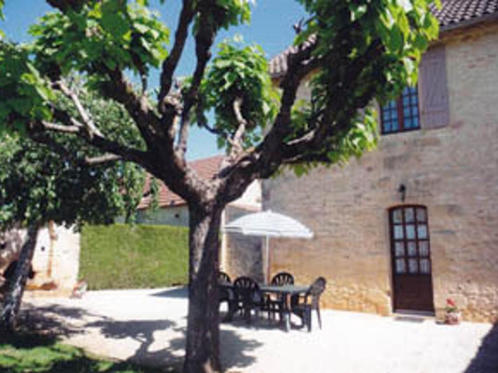 une table et des chaises avec un parasol en face d'un bâtiment dans l'établissement Gîte confortable proche Sarlat, jardin, ping-pong, parking - FR-1-616-403, à Proissans