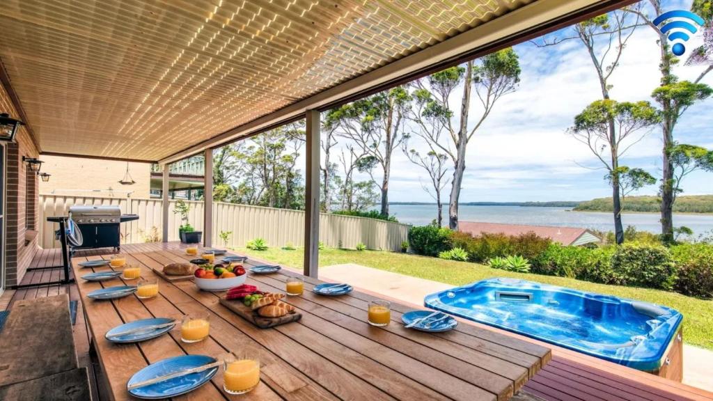 a patio with a table with food and a swimming pool at Sandy C in Culburra Beach