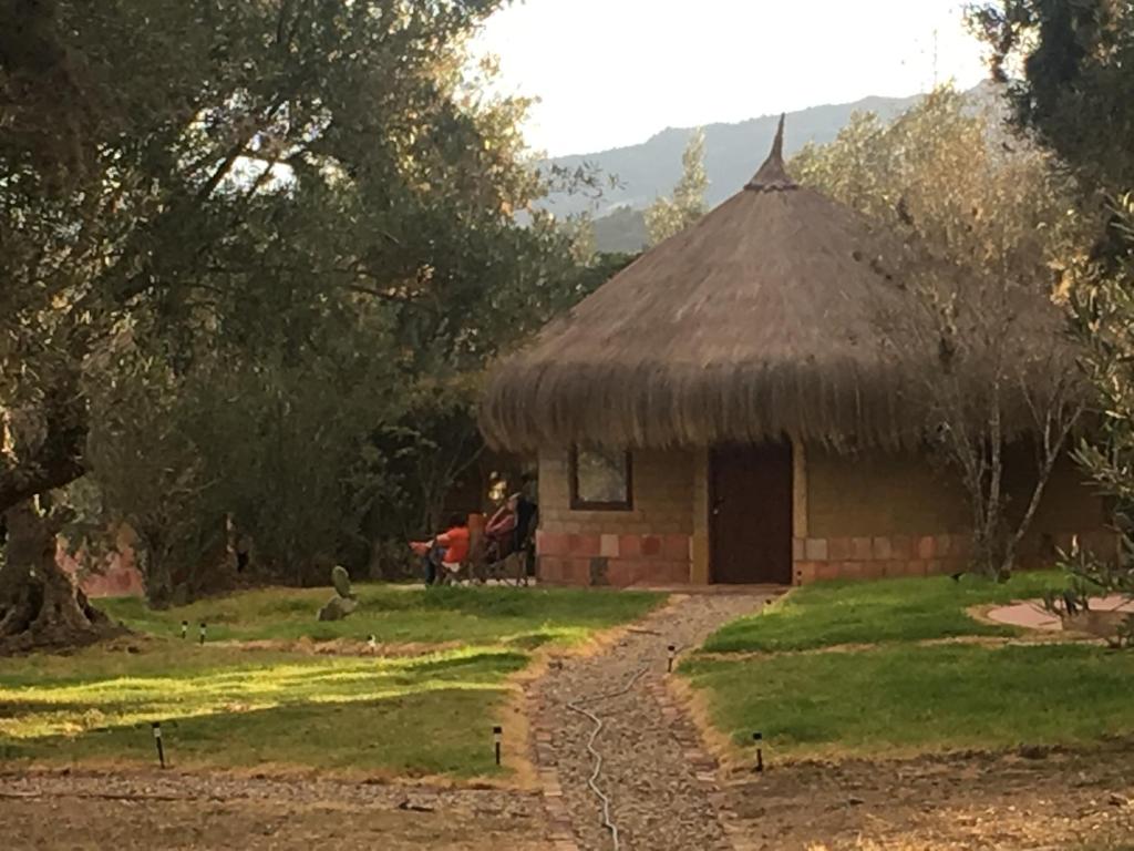 a small hut with a thatched roof and a path at Habitación Ancestral Sol Muisca in Villa de Leyva