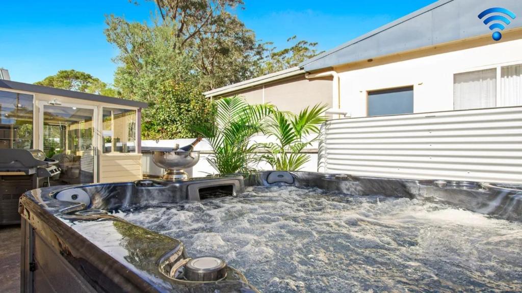 Un jacuzzi en un patio al lado de una casa. en Sandy Shores, en Callala Bay
