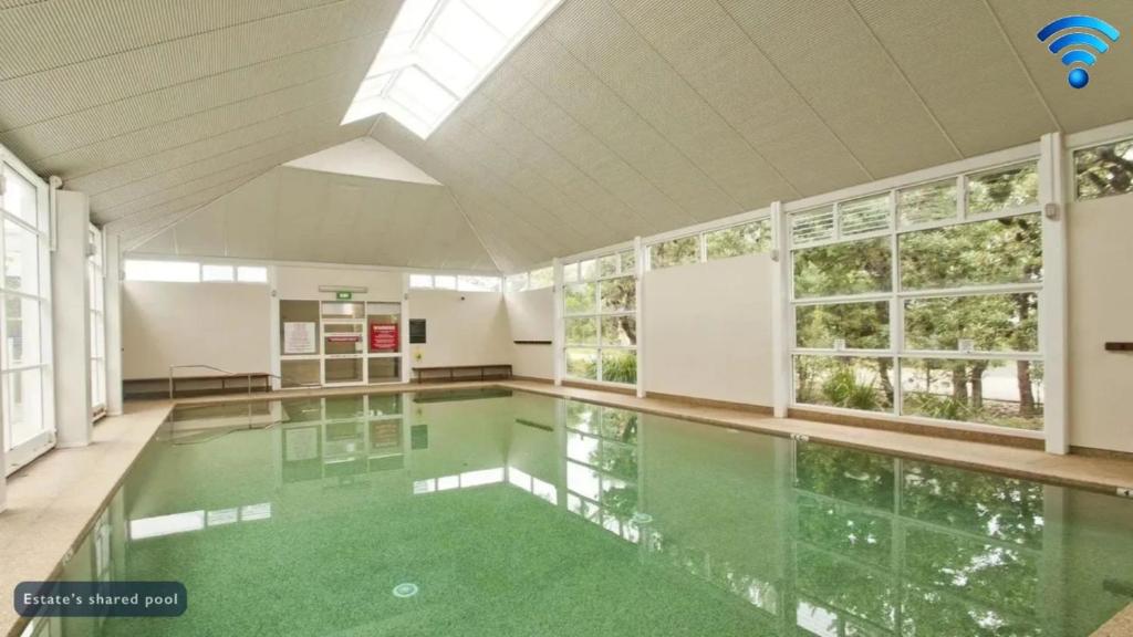 una gran piscina con suelos verdes y ventanas en Sea Whispers, en Callala Beach