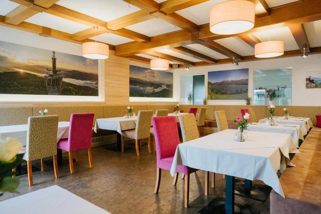 a restaurant with white tables and pink chairs at Der Thomashof in Sankt Jakob im Rosental