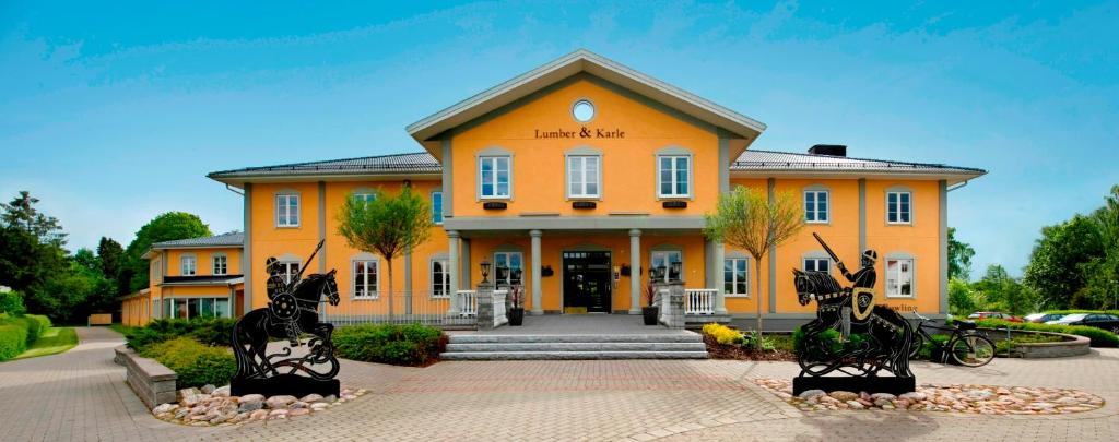 a large orange building with two statues in front of it at Lumber & Karle in Kvänum