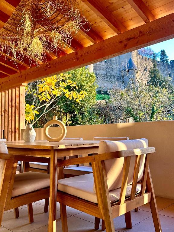 - une table et des chaises en bois sur une terrasse couverte avec une fenêtre dans l'établissement Maison Henriette - Au plus près de la Cité Médiévale, à Carcassonne