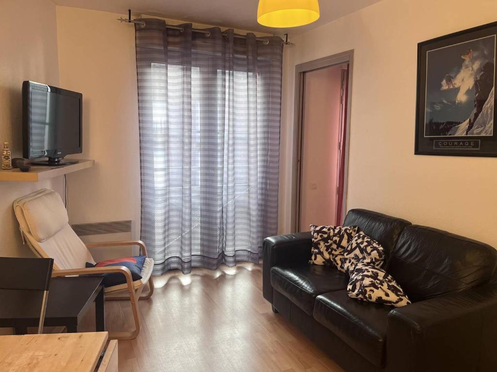 un salon avec un canapé en cuir noir et une télévision dans l'établissement Appartement cosy Cauterets près des télécabines - FR-1-812-38, à Cauterets