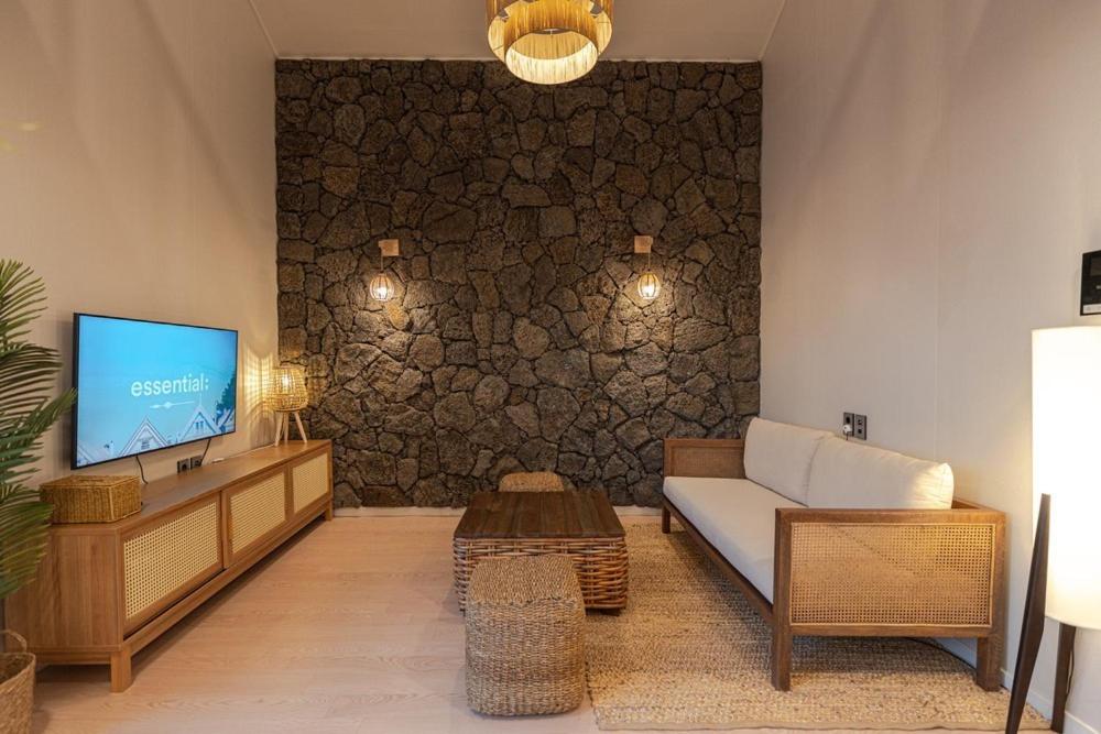 a living room with a couch and a tv at Jeju at Aewol Forest 402 in Jeju
