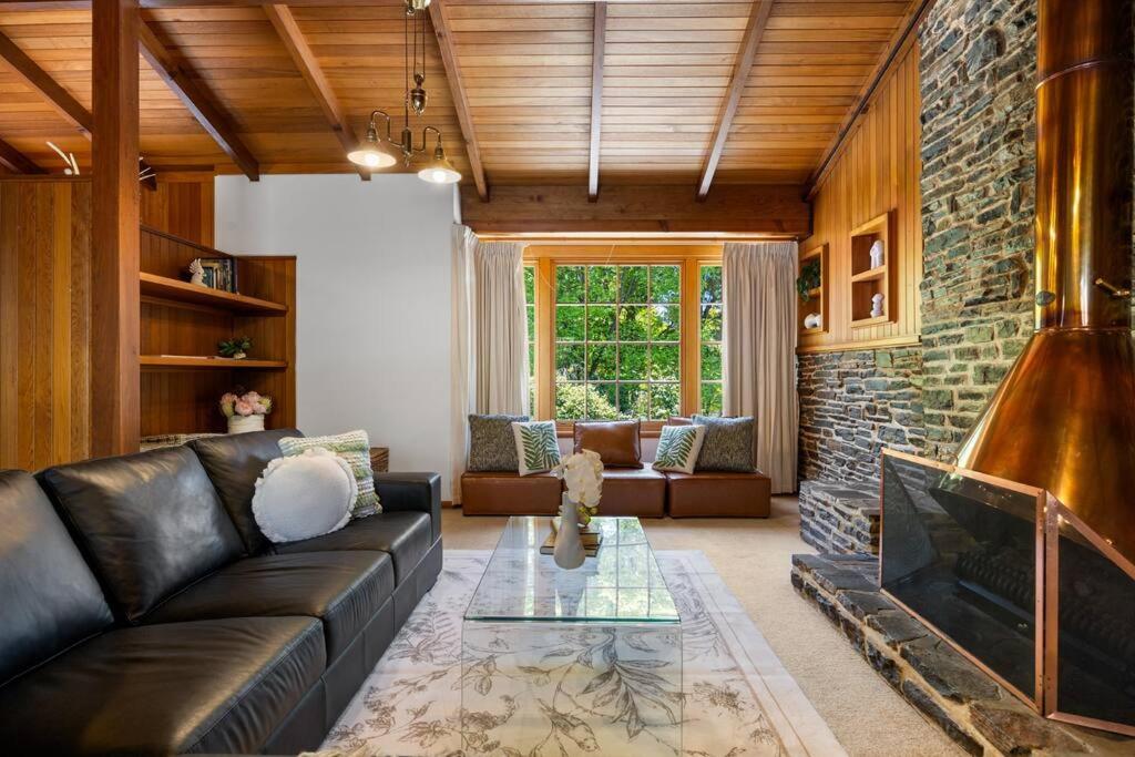 a living room with a leather couch and a fireplace at Amber Whisper - In the Hills with Pool & Tennis Court in Hahndorf