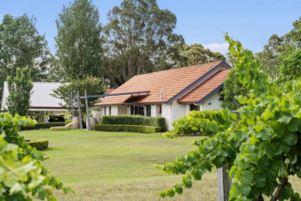 una casa con tetto spiovente e un cortile di Travertine Vineyard Retreat - Stay Among the Vines a Pokolbin