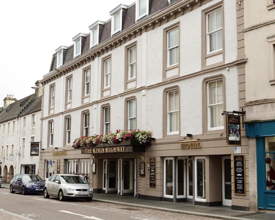 a large white building on a street with cars parked in front at The King's Highway Wetherspoon in Inverness