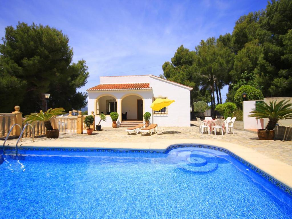 a villa with a swimming pool in front of a house at Holiday Home Caleta in Jávea