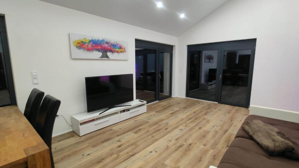 a living room with a large tv and a wooden floor at Moderne Penthouse mit großer Terasse in Bad Laasphe