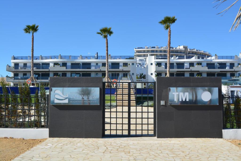 a black gate with palm trees in front of a building at ROMERO APARTMENTS-ARENALES DEL SOL in Arenales del Sol