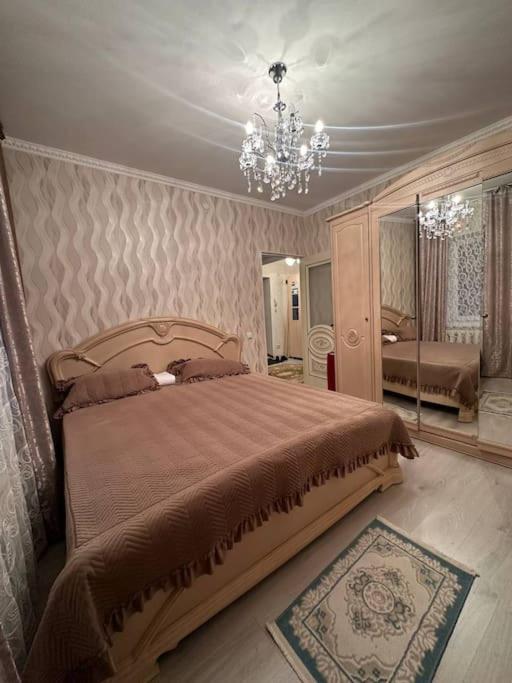 a bedroom with a bed and a chandelier at 3х комнатная по Толе би in Taraz