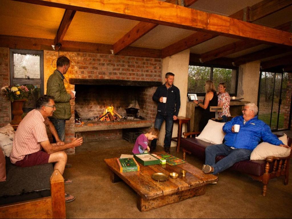 a group of people in a living room with a fireplace at Merwespont Guesthouses#DieHouthuis#Die Wyntenke#A Snoozer's Cottage# in Bonnievale