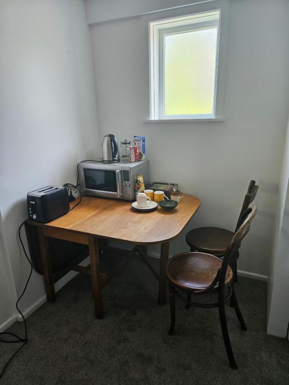 a table with a microwave and two chairs in a room at Private room in Wellington with views in Wellington