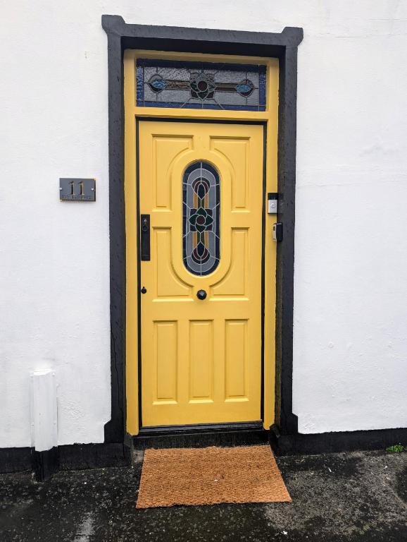 a yellow door on a white building at Ivy Townhouse Derry in Derry Londonderry