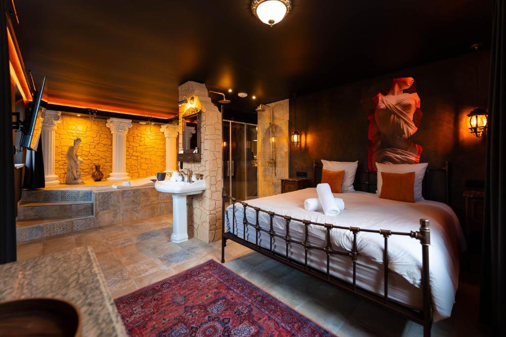 a bedroom with a bed and a bathroom with a sink at La Suite de Vénus - Chambre à thème Love Room Jacuzzi et Pièce Secrète - Évasion pour deux in Schirrhein
