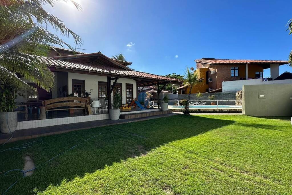 ein Hinterhof eines Hauses mit einem Rasen in der Unterkunft Casarão 100 metros da praia in Barra de São Miguel
