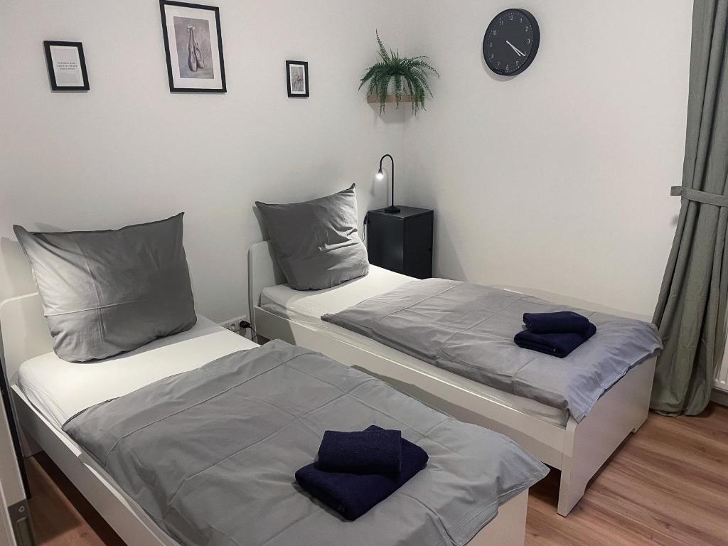 two beds in a room with a clock on the wall at bookandstay24 Die-burg 4 Zimmerwohnung mit Küche und Balkon bei Darmstadt, Frankfurt, RheinMain Gebiet in Dieburg