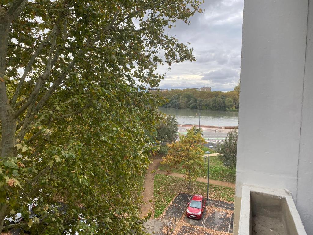 une voiture rouge garée dans un parking à côté d'une rivière dans l'établissement Apparemment Toulouse centre, à Toulouse