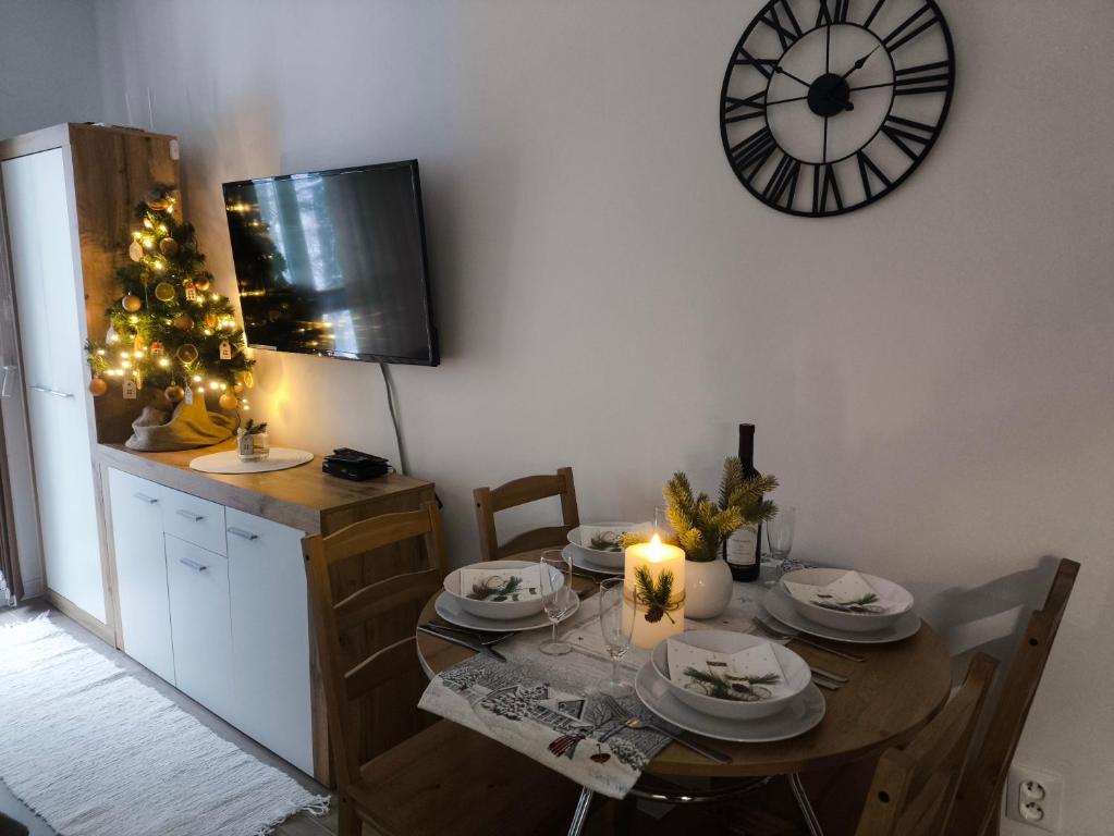 un comedor con una mesa y un reloj en la pared en Apartman Ema, en Donovaly