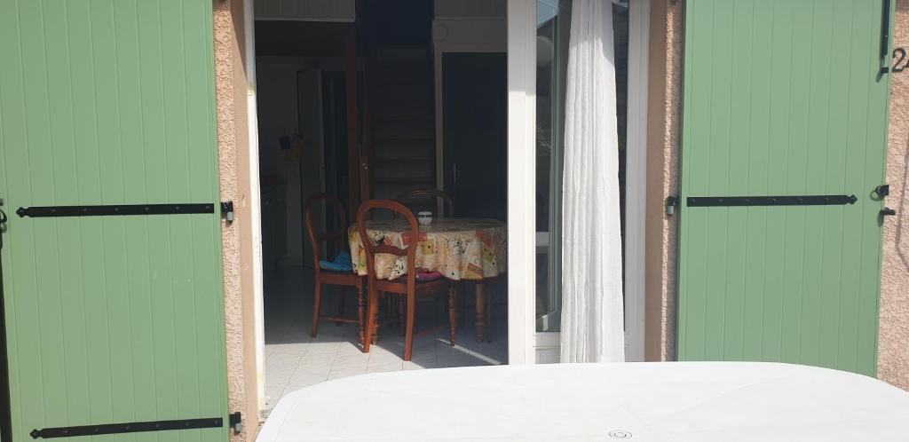 une porte ouverte menant à une chambre avec une table et une chaise dans l'établissement Petite maison en Ardèche, à Saint-Martin-dʼArdèche