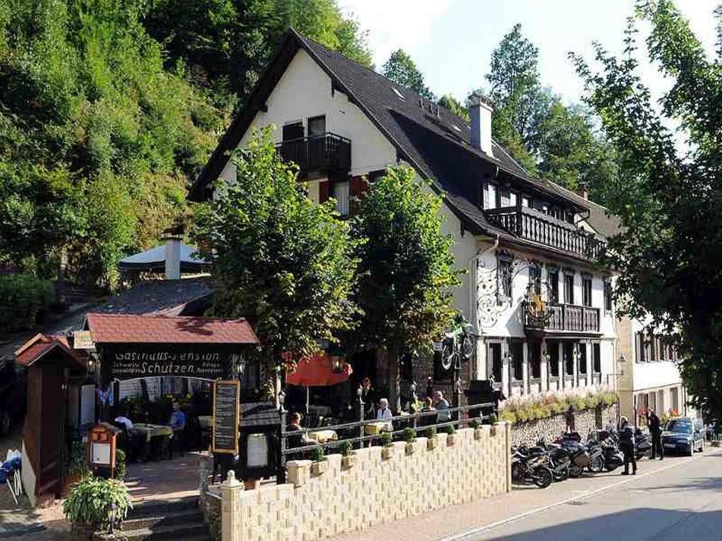 ein großes weißes Gebäude mit Leuten, die draußen sitzen in der Unterkunft Hotel Schützen in Bad Peterstal-Griesbach