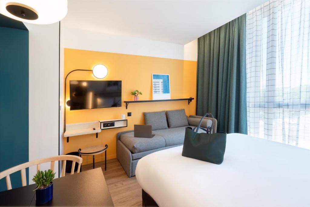 une chambre d'hôtel avec un lit et un canapé dans l'établissement Aparthotel Adagio Access Rouen Centre Cathédrale, à Rouen