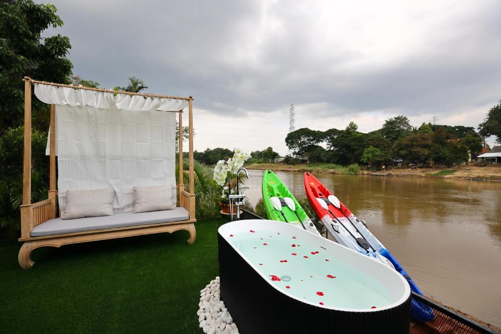 a boat with a chair and a bathtub on the side of a river at Mata villa มาตา วิลล่า in Chiang Mai