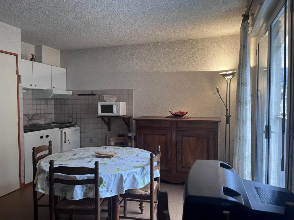 une cuisine avec une table avec des chaises et un micro-ondes dans l'établissement Studio central 4 pers, proche télécabines, cellier à skis - FR-1-812-16, à Cauterets