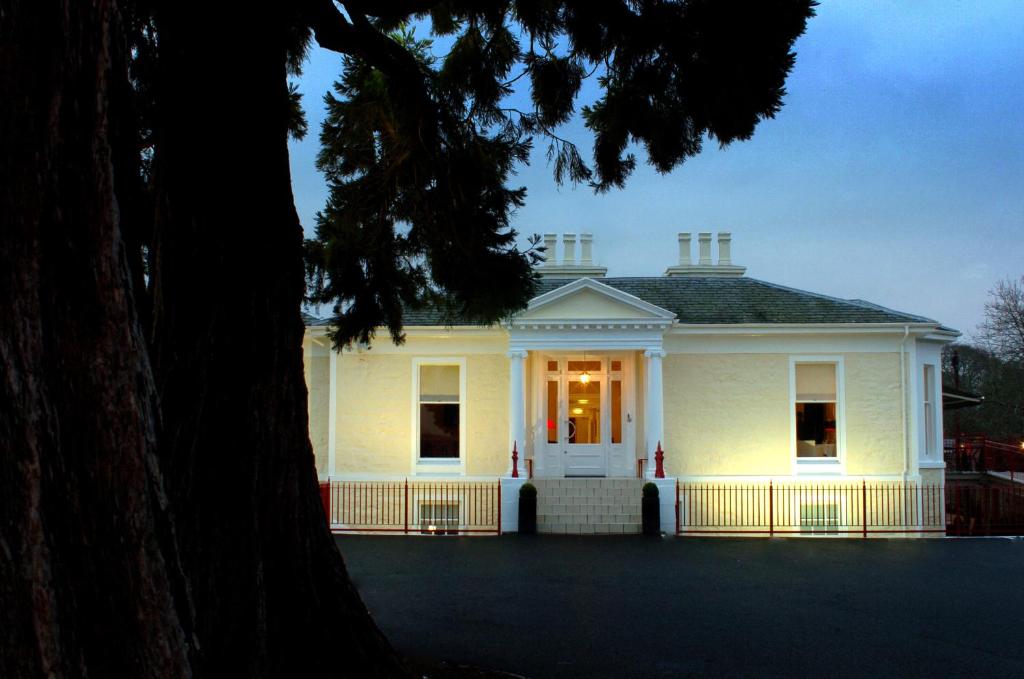 a white house with a porch and a tree at Rocpool Reserve Hotel & Restaurant in Inverness