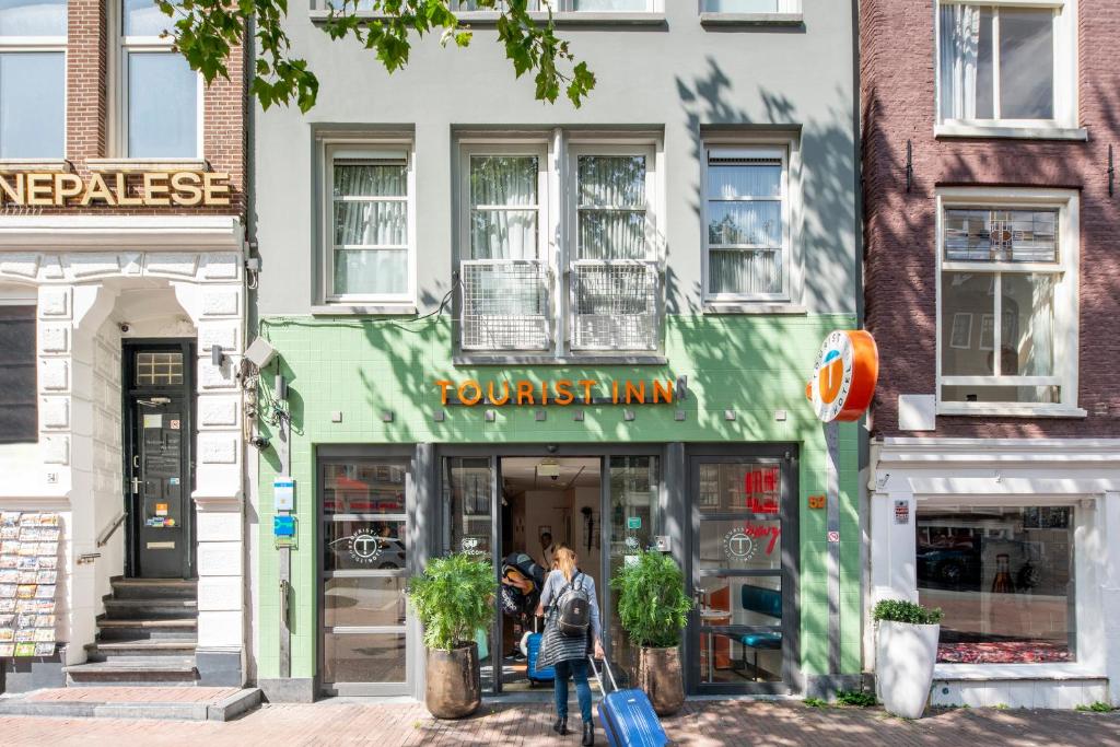 a woman walking down a street in front of a store at Tourist Inn Hotel Amsterdam in Amsterdam