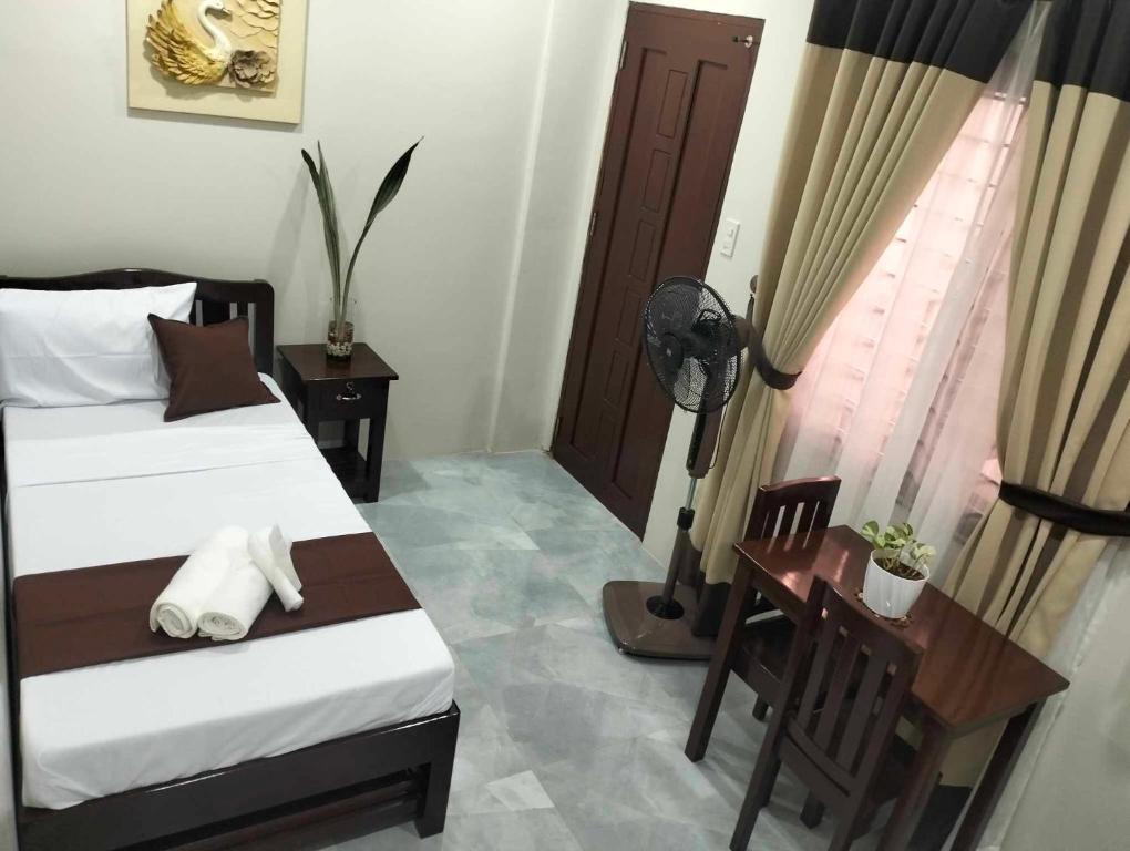 プエルト・プリンセサにあるJMorino Pension Houseのベッドと机と窓のある寝室