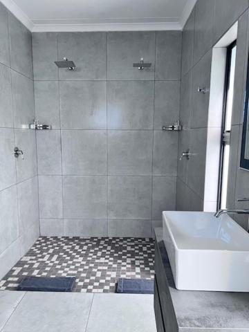 bagno con doccia, vasca e lavandino di Turaco Lodge - No Loadshedding a Marloth Park