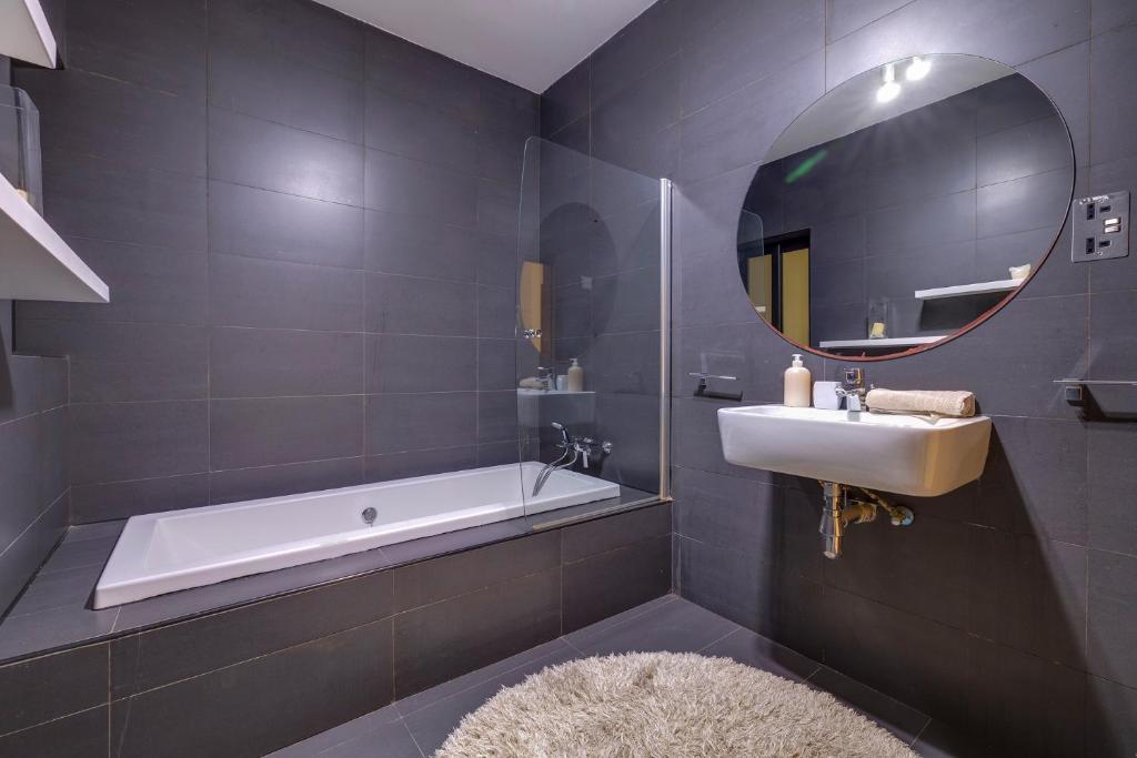 a bathroom with a tub and a sink and a mirror at Modern 2BR Sliema Apartment in Sliema