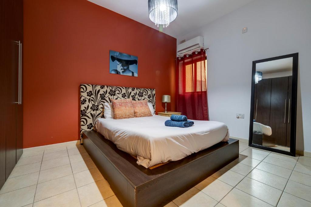 a bedroom with a large bed with orange walls at Modern 2BR Sliema Apartment in Sliema