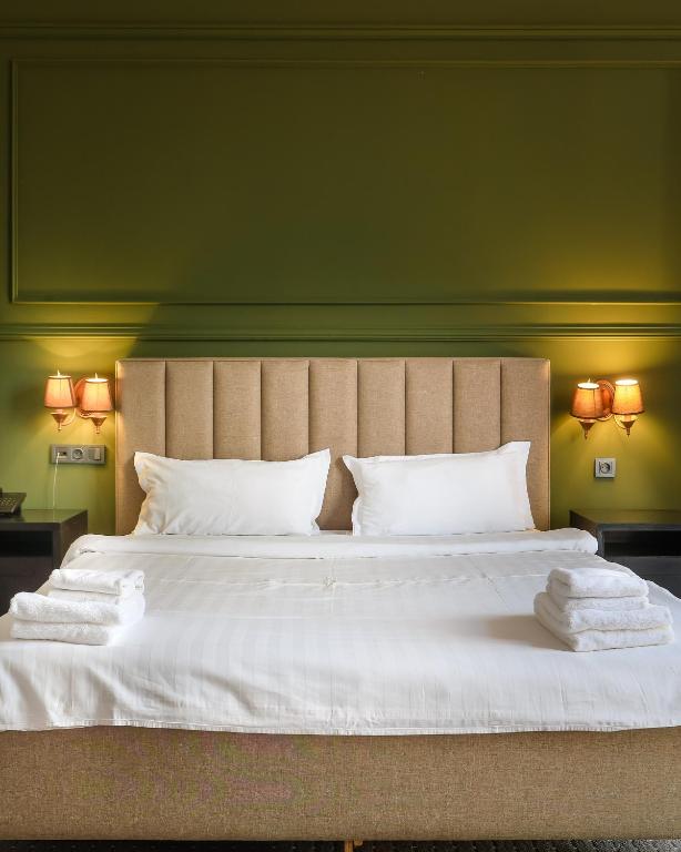 a bedroom with a large bed with white sheets and pillows at GRAND OPERA HOTEL in Almaty