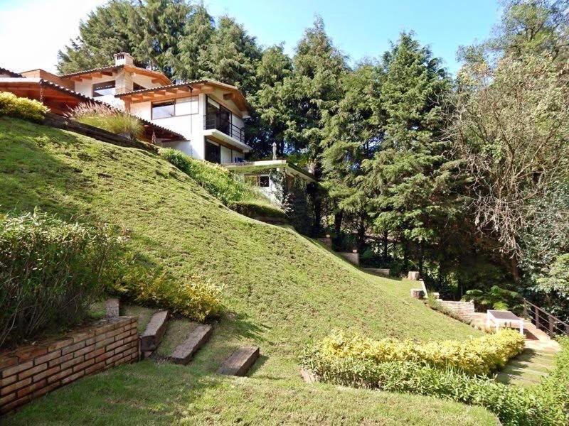 a house sitting on top of a grassy hill at River Home in Valle de Bravo