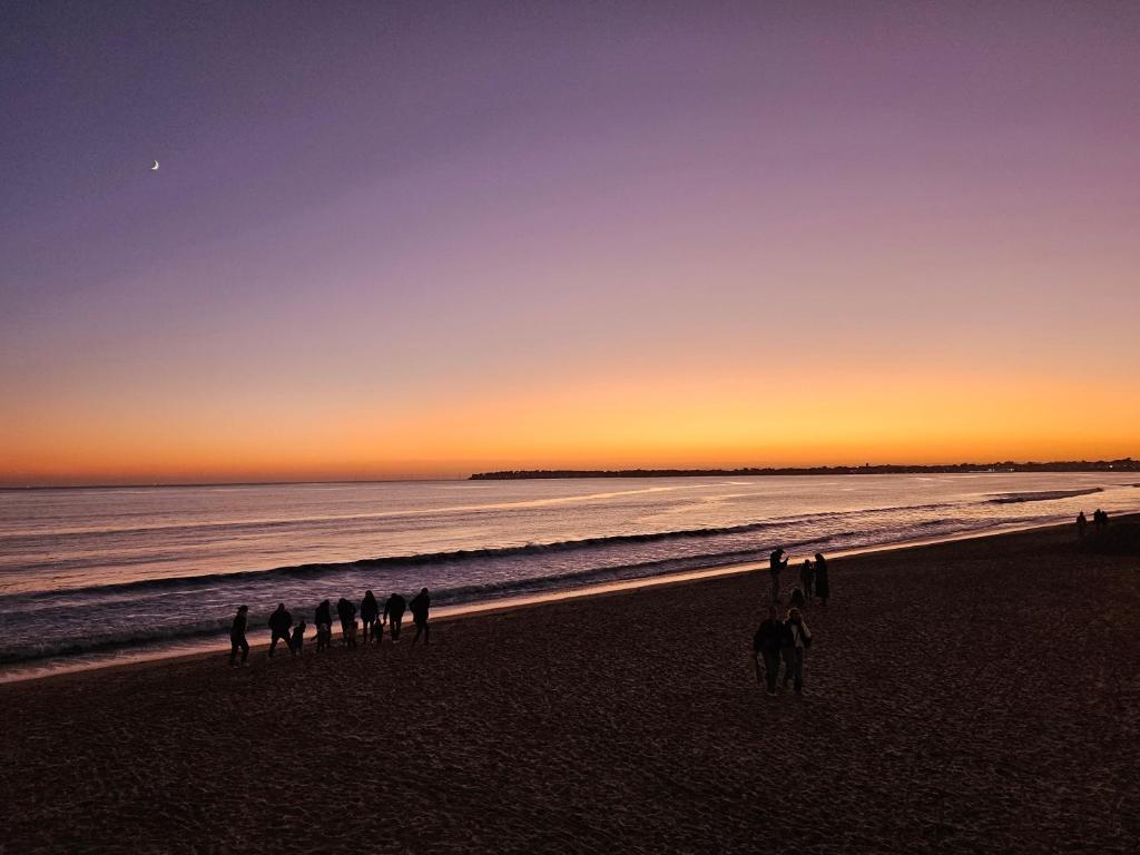 een groep mensen die bij zonsondergang op het strand lopen bij Le Capitole - Studio Plage Benoit - Escapade Hivernale in La Baule