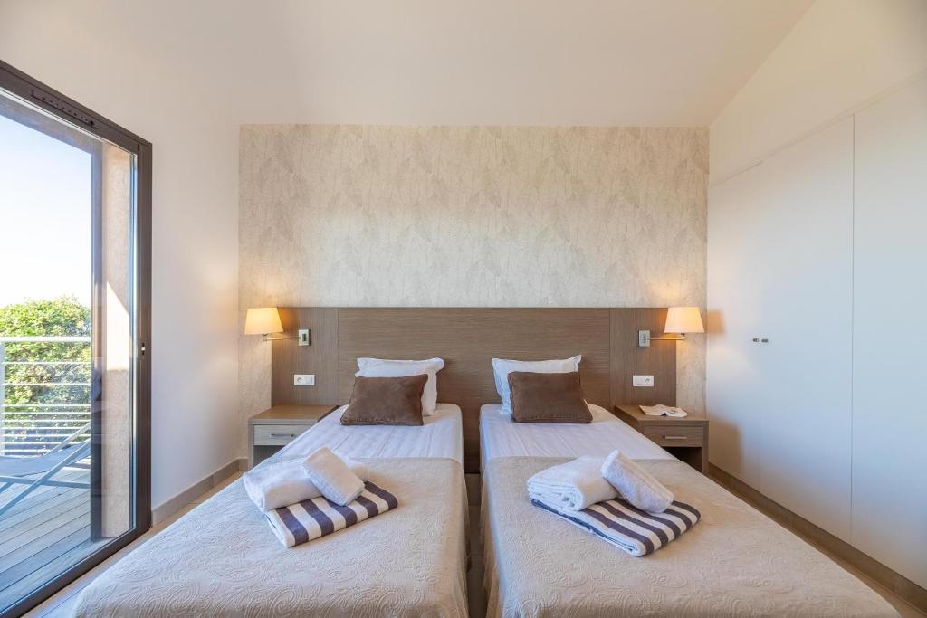 a bedroom with two beds and a large window at Résidence Les Terrasses de Rondinara in Bonifacio