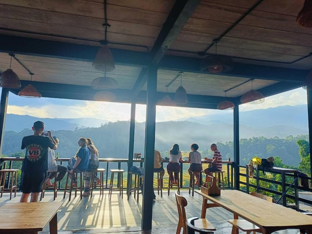 a group of people sitting at tables on a deck at Motho Homestay โมโทโฮมสเตย์ in Chom Thong