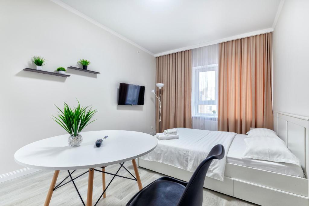 a white bedroom with a white bed and a white table at RAISSON APARTHOTEL AM85 Хан Шатыр in Taldykolʼ