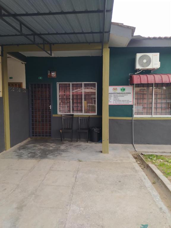 a building with two chairs in front of it at Atbas Homestay No 1 in Seri Iskandar
