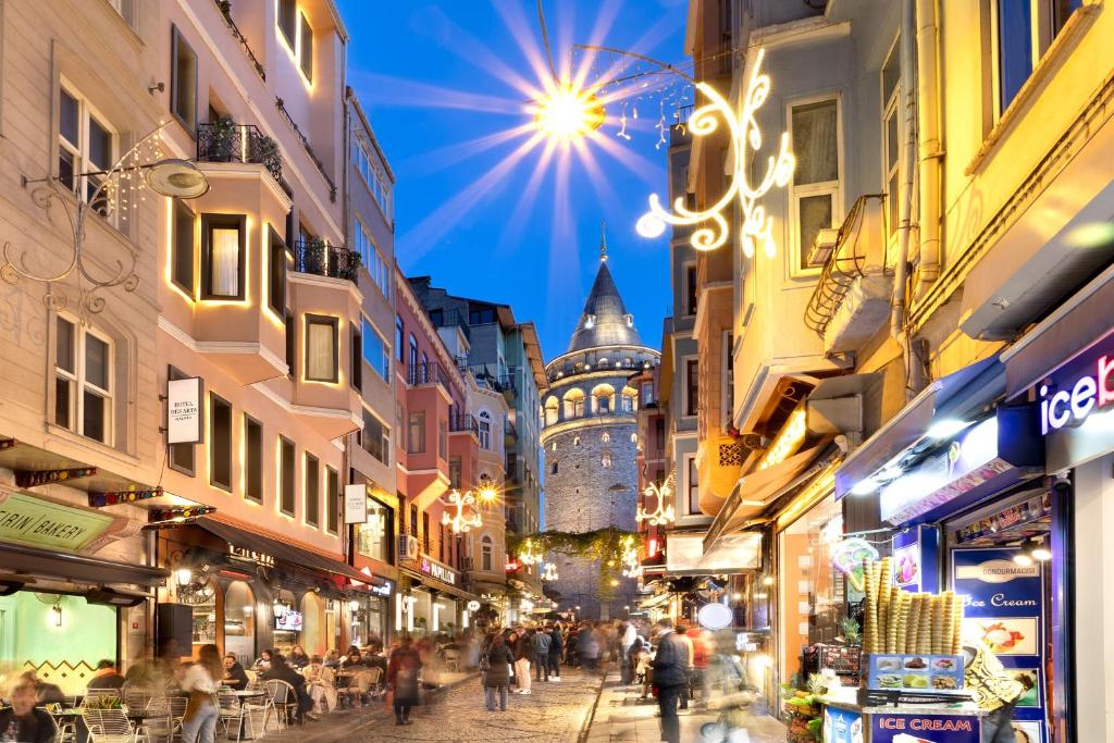 a group of people walking down a street with a clock tower at Hotel Des Arts Galata in Istanbul