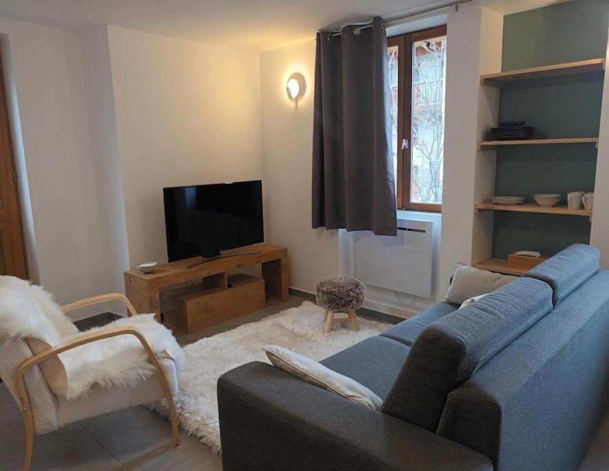 un salon avec un canapé bleu et une télévision dans l'établissement Chalet Barbarine au coeur des 3 Vallées, à La Combe