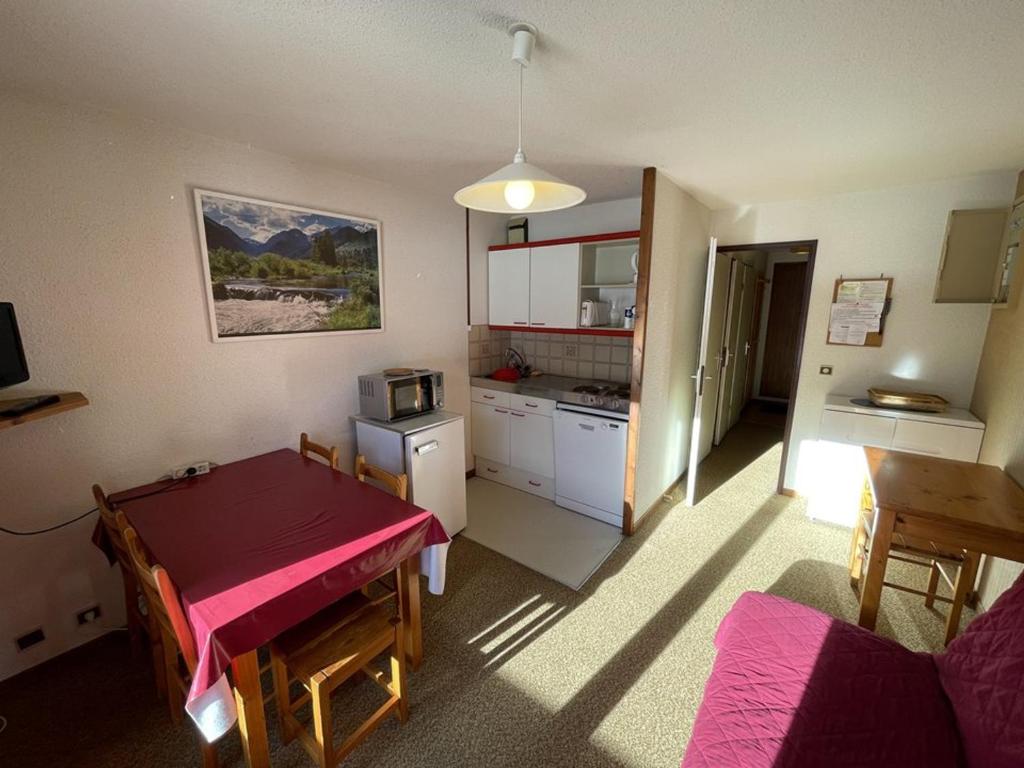 une chambre avec une table et une cuisine avec une table rouge dans l'établissement Charmant T2 cabine au pied des pistes avec balcon et commodités - FR-1-787-85, à Laveissière