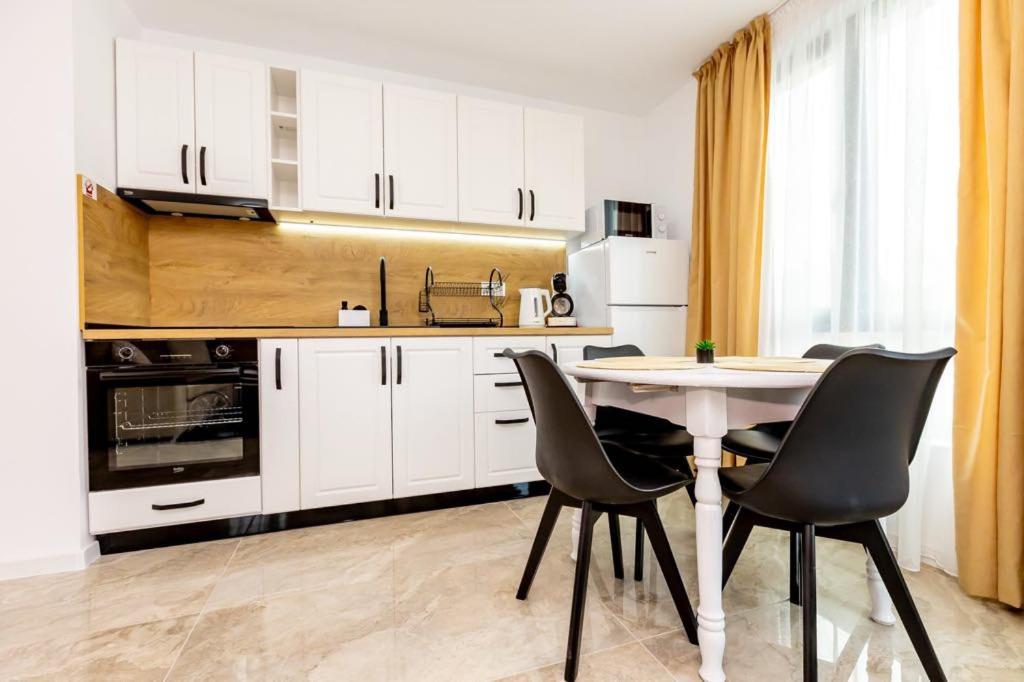 a kitchen with white cabinets and a table and chairs at Apartment Golden Park in Sandanski