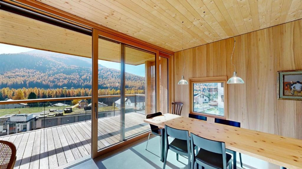 ein Esszimmer mit einem Tisch und einem großen Fenster in der Unterkunft Apartment Roseg Nouva in Pontresina