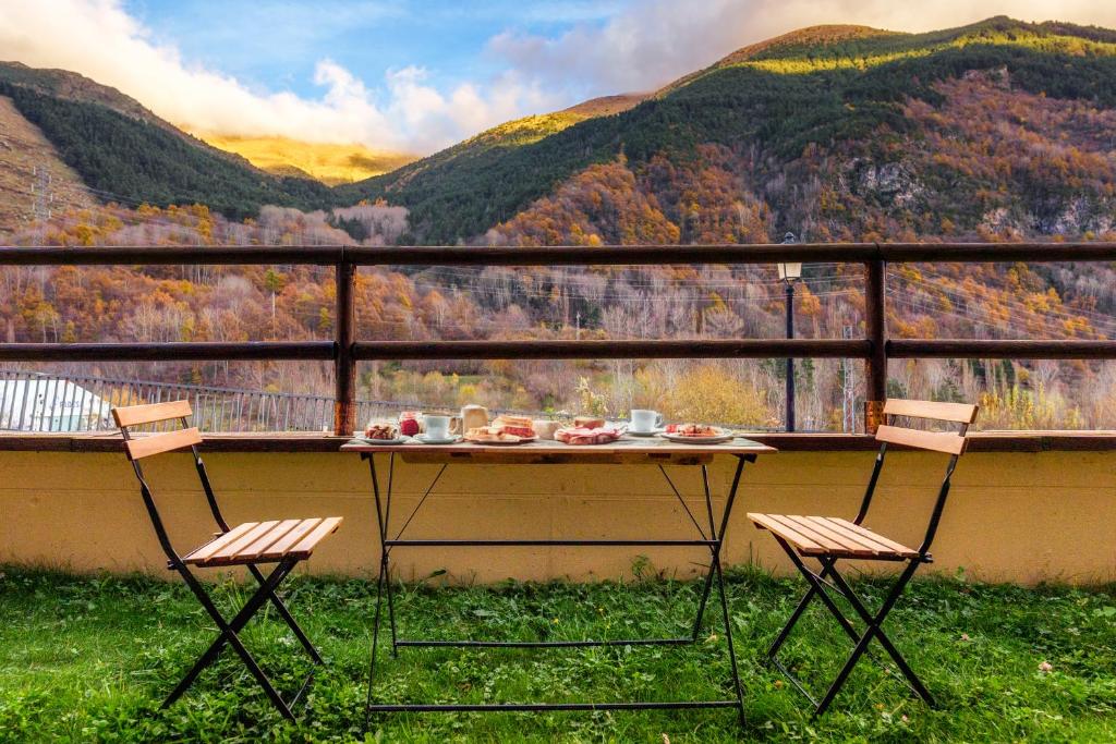 a table and two chairs on a balcony with mountains at Apartament Vega - Vall Fosca - L'Amfitriona in Espúy