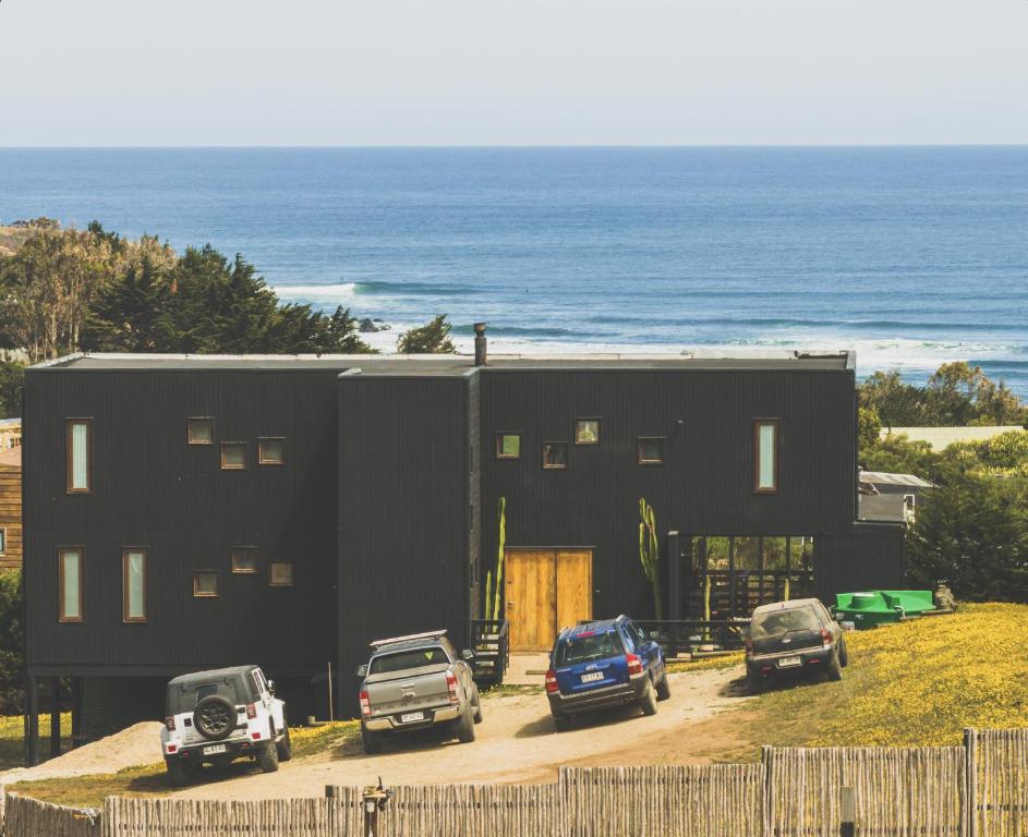una casa negra con coches aparcados delante de ella en Casa Alma - Punta de Lobos, en Pichilemu